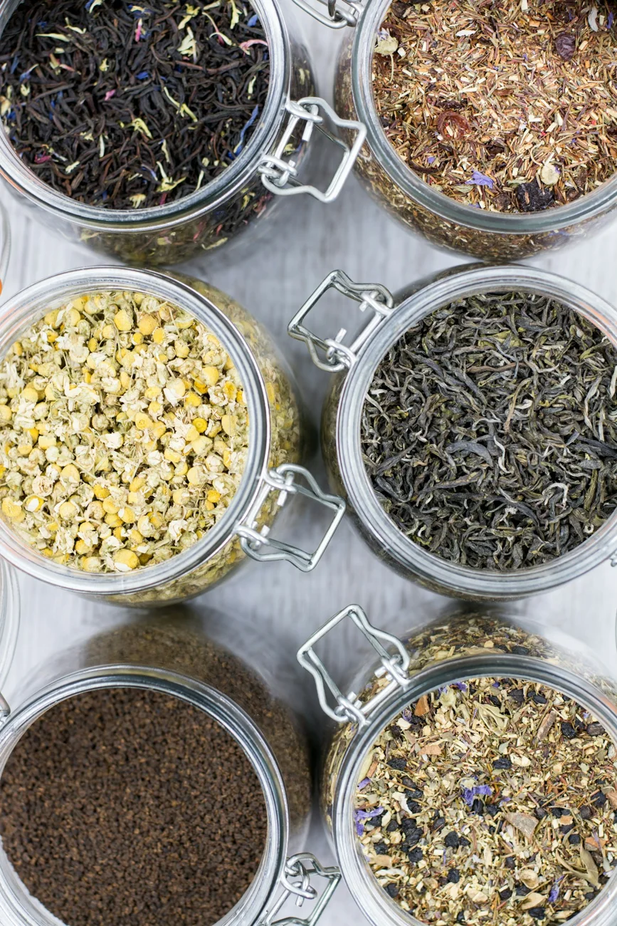 Detalle de hojas de té y distintos ingredientes en frascos de vidrio
